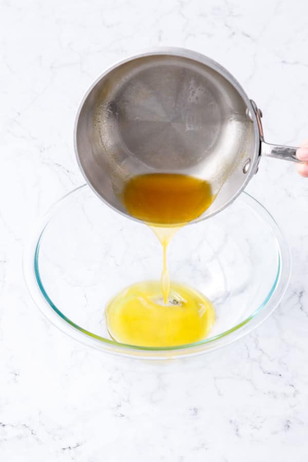 Pouring passionfruit base mixture into a glass mixing bowl.