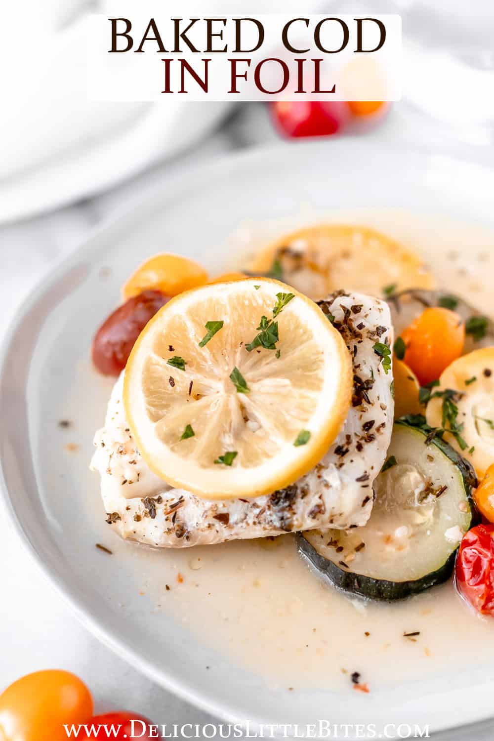 Baked cod and vegetables topped with lemon on a white plate with text overlay.