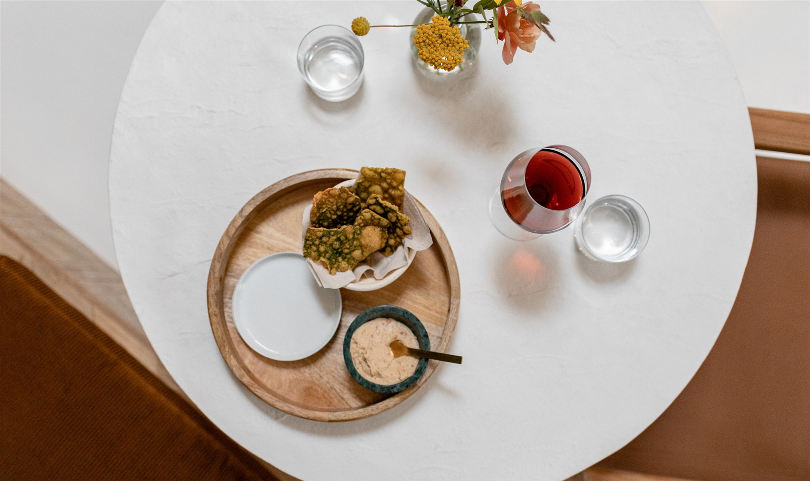 overhead view of white table with red wine glass and food