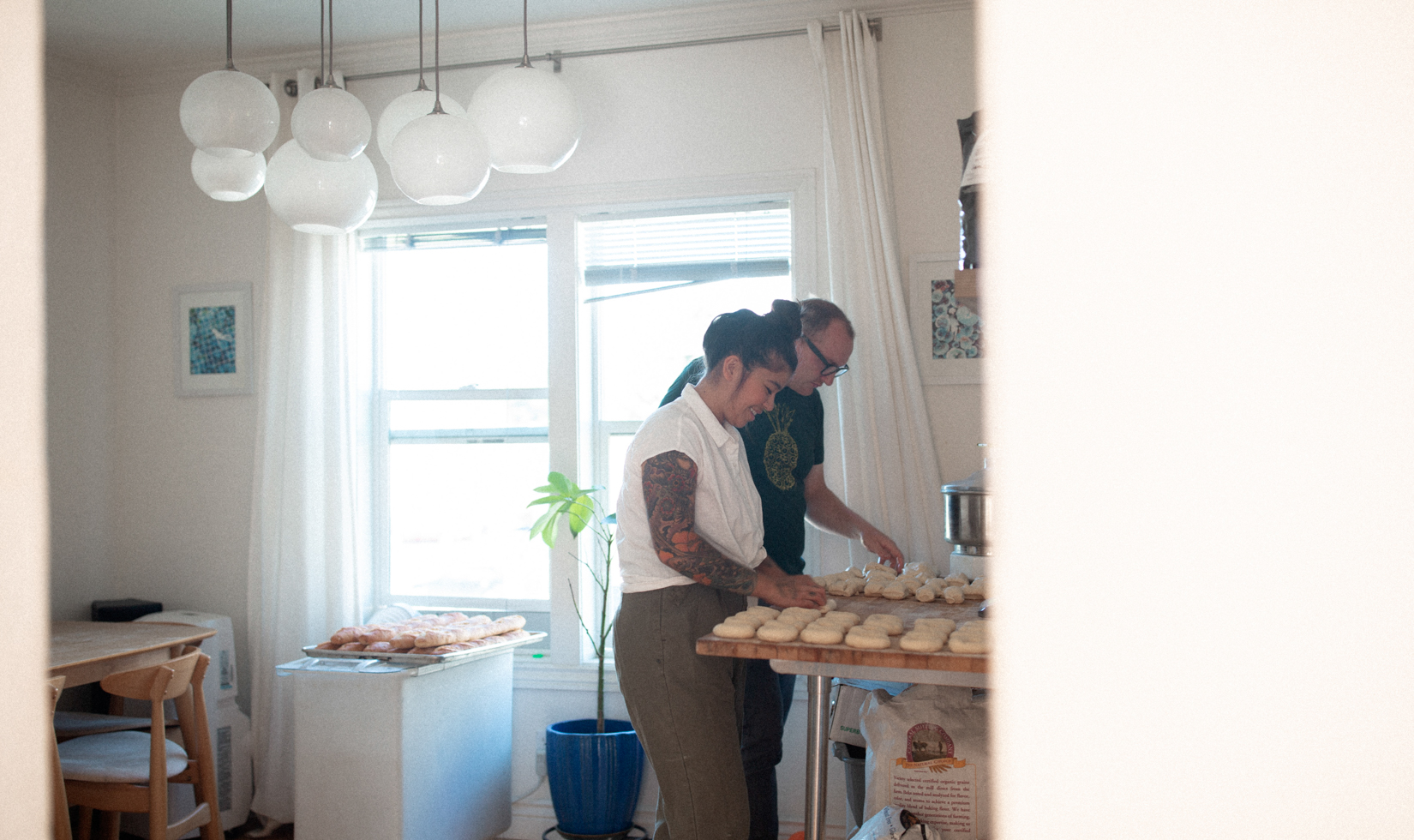 husband and wife bake bread in sunny kitchen