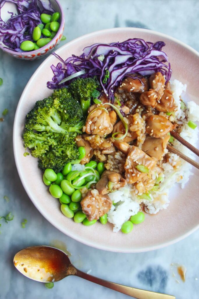 Glossy chicken teriyaki on top of rice with red cabbage, edamame and broccoli.