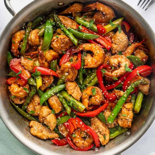 Chicken and shrimp stir fry in a pan.