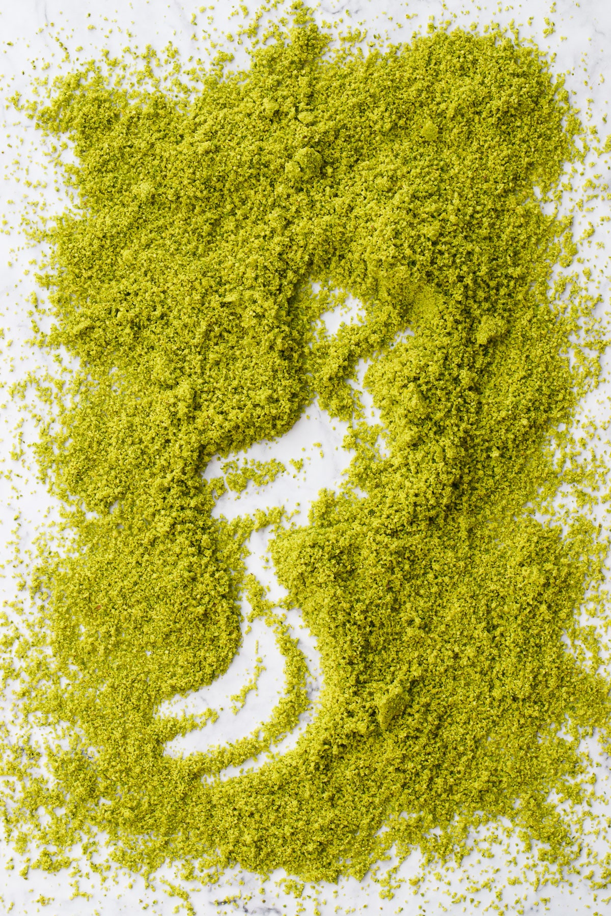 Rough rectangle of homemade pistachio flour with a squiggle dragged through the middle showing the marble background underneath.