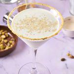A martini glassed rimmed with crushed pistachios and filled with pistachio martini.