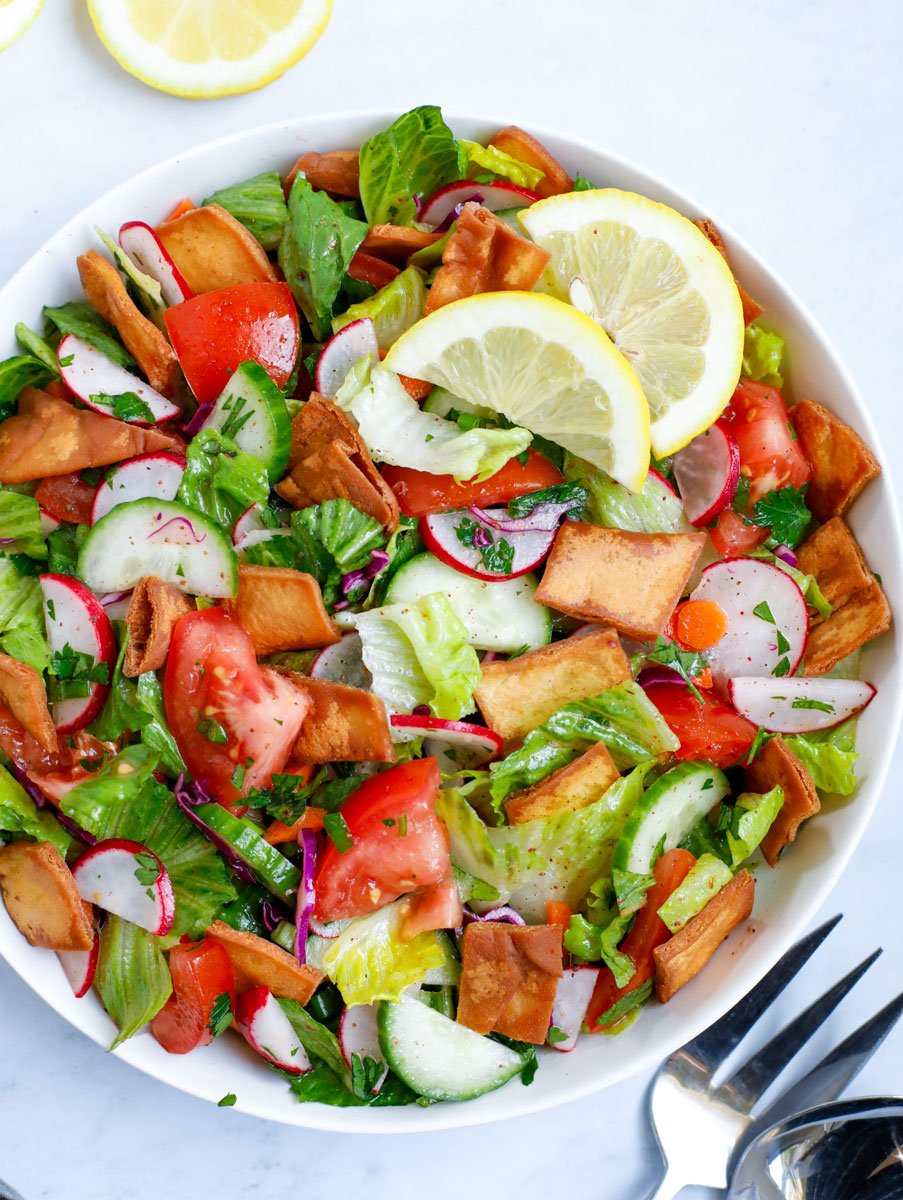 Lebanese Fattoush salad served in a white bowl with lemon slices.