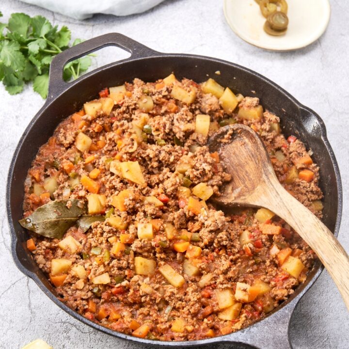 A cast iron pan with the ground beef and vegetables mixed together.