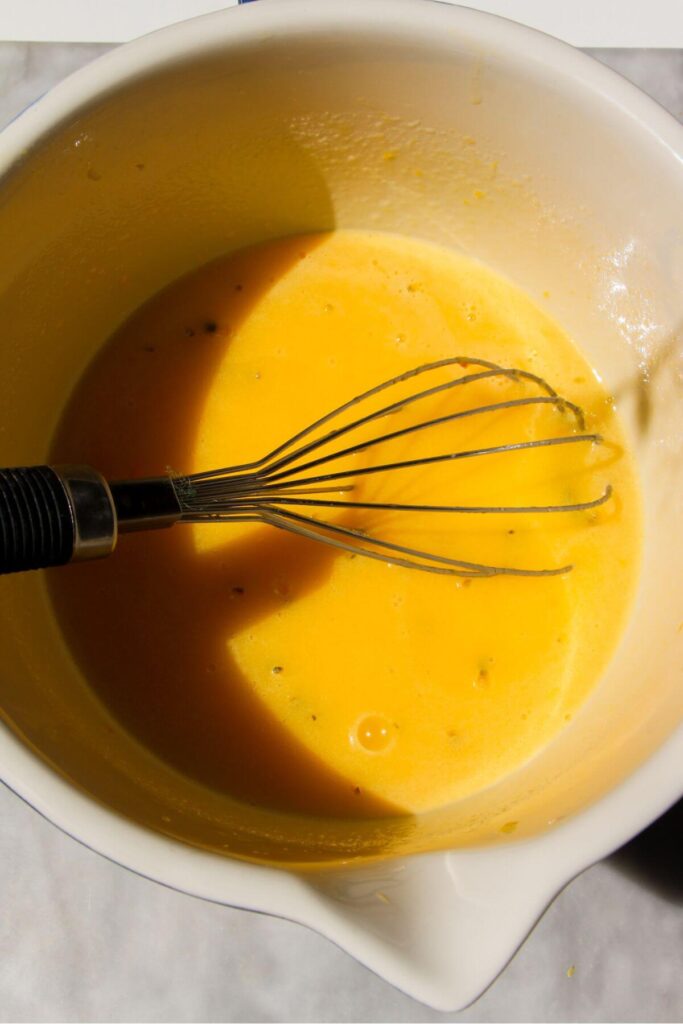 Lemon passionfruit curd whisked in a hite and blue bowl.