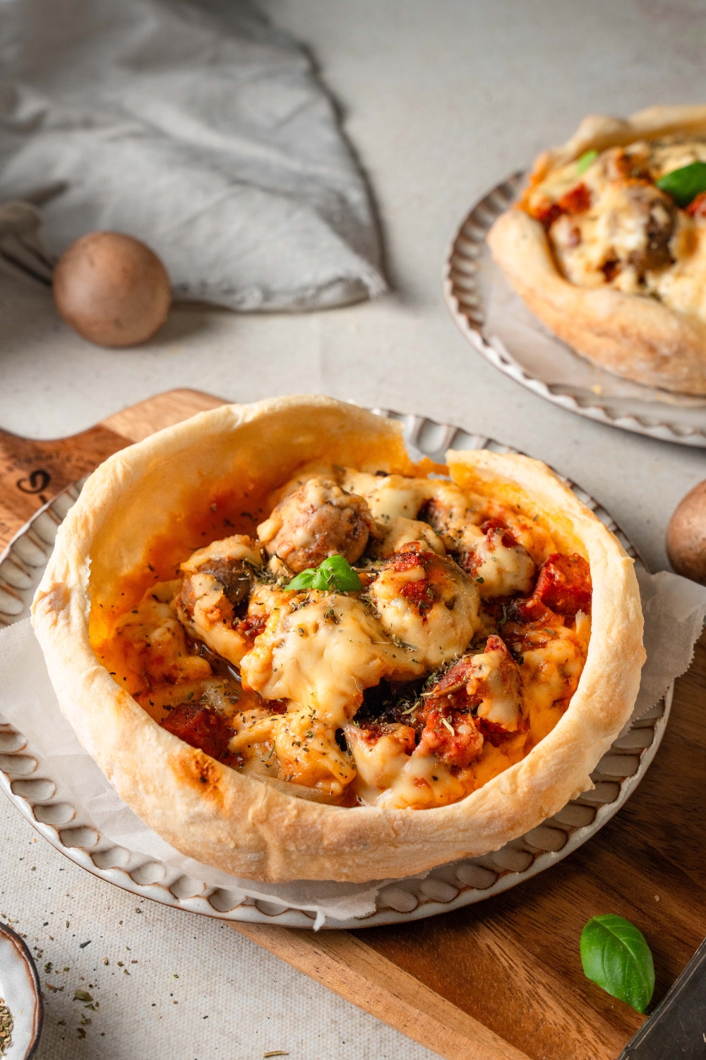 A baked Chicago pizza pot pie sits on a plate. The cheese has melted over the mushrooms.
