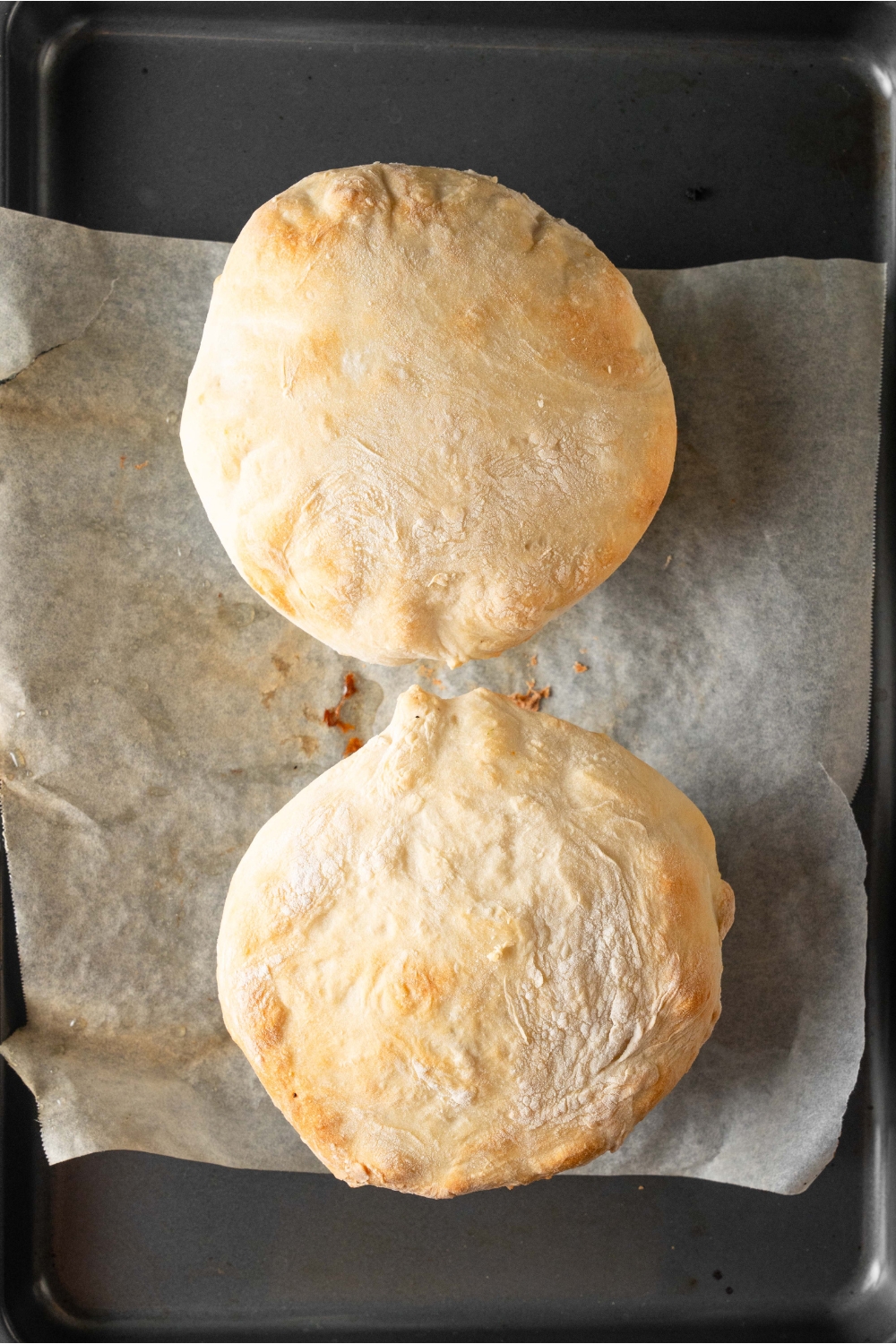Two baked pot pies are on a baking sheet lined with parchment paper.