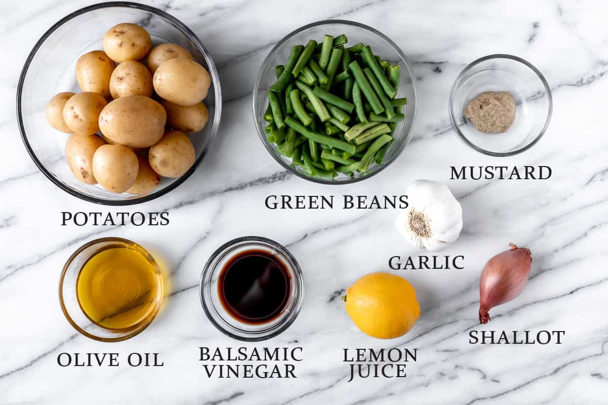 Ingredients needed to. make green bean potato salad on a marble background with text overlay.