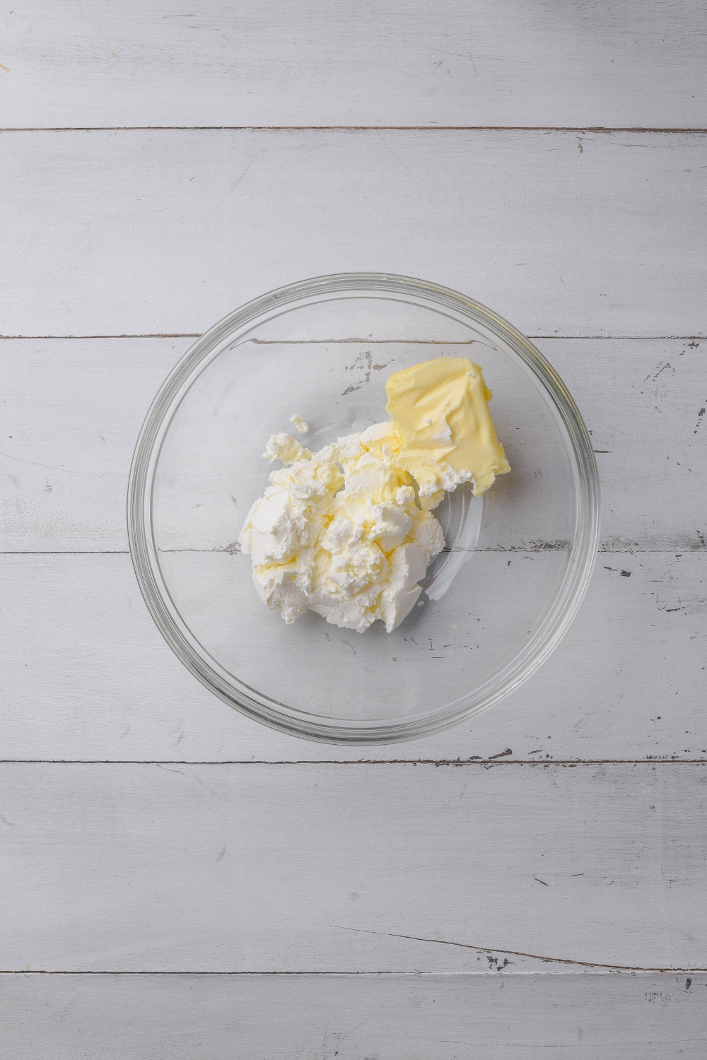 A glass bowl holds butter and cream cheese ready to be combined.