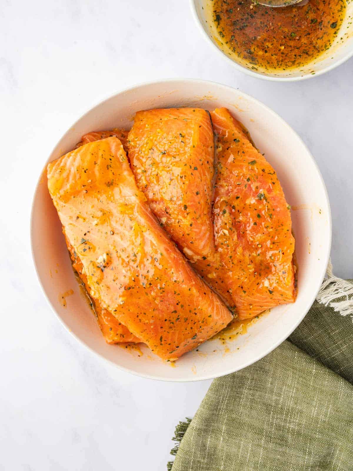 Marinated salmon filets in a bowl.