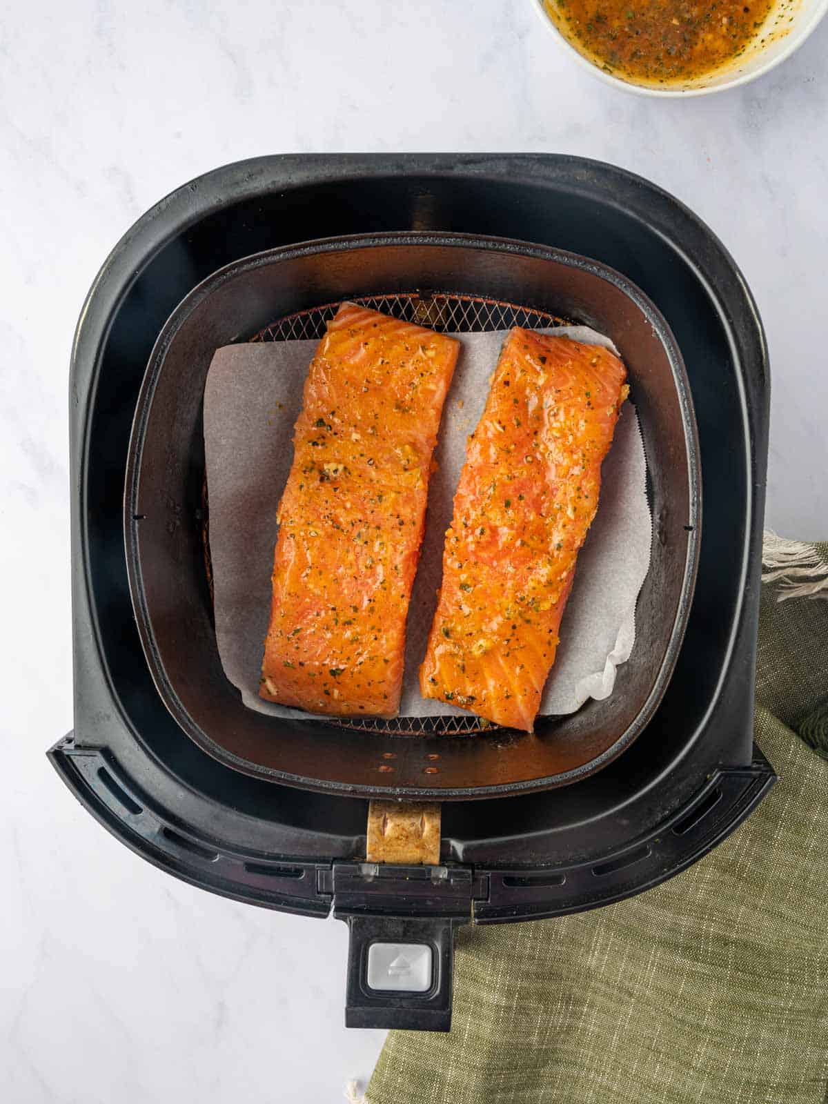 Marinated salmon filets in an air fryer basket.