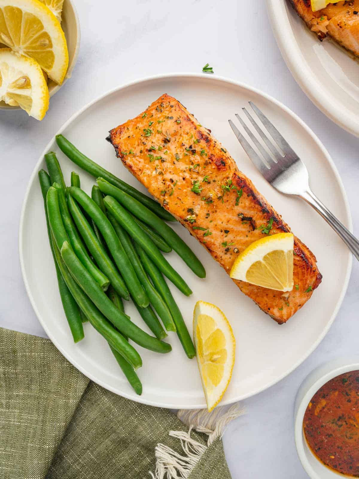 Salmon filet on a plate with green beans and a fork.
