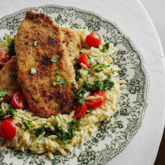 Chicken cutlet on plate with orzo