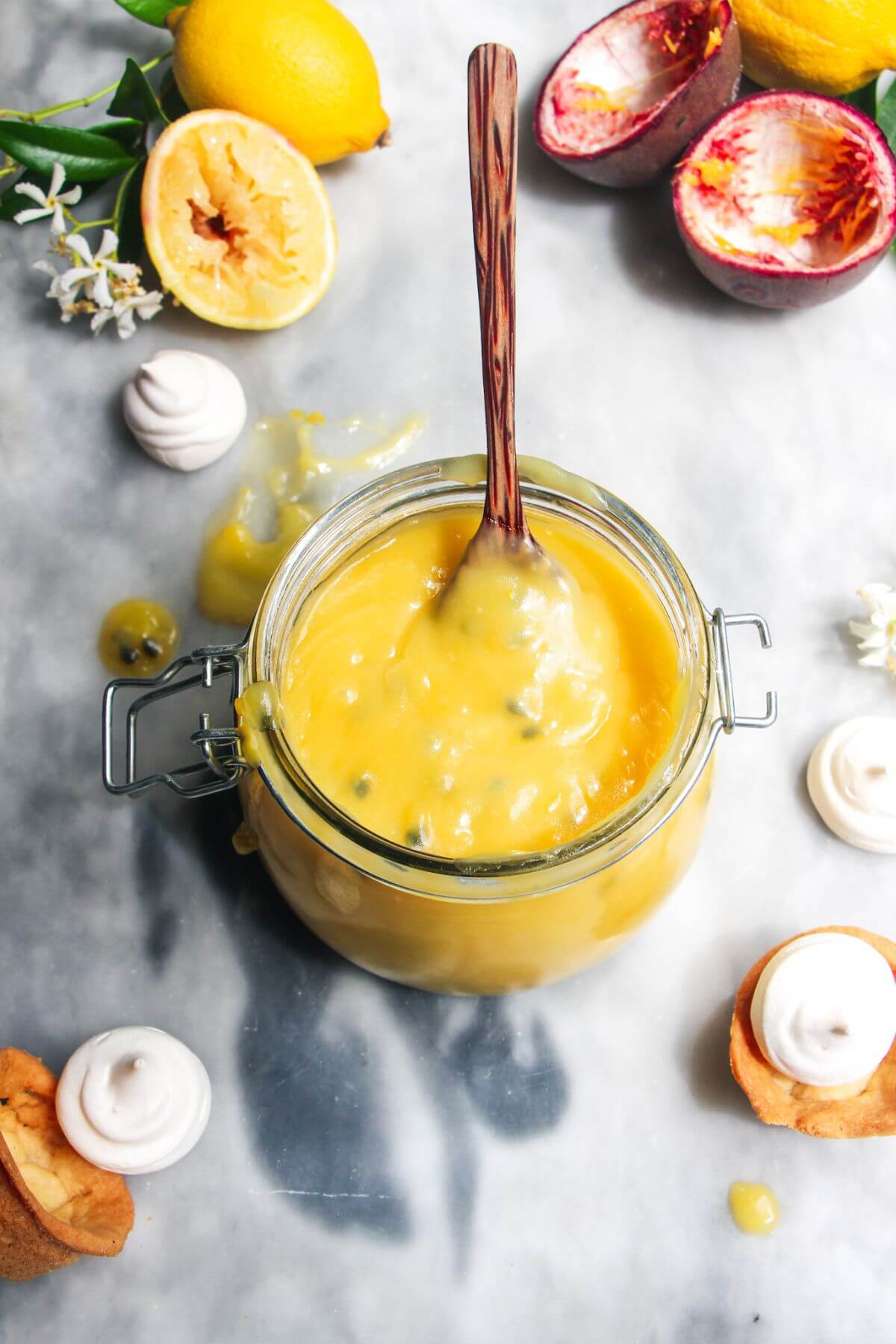 Lemon and passionfruit in a glass jar with a spoon in it.