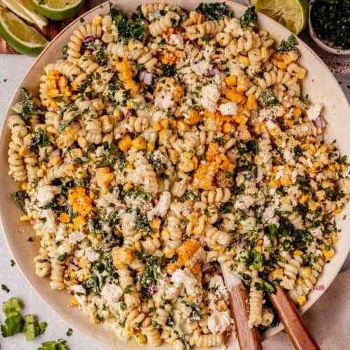 mexican street corn pasta salad in a serving bowl with wooden spoons