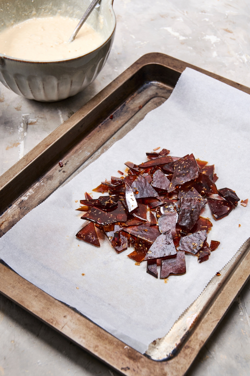 Shards of maple syrup are piled on a parchment paper lined baking sheet.