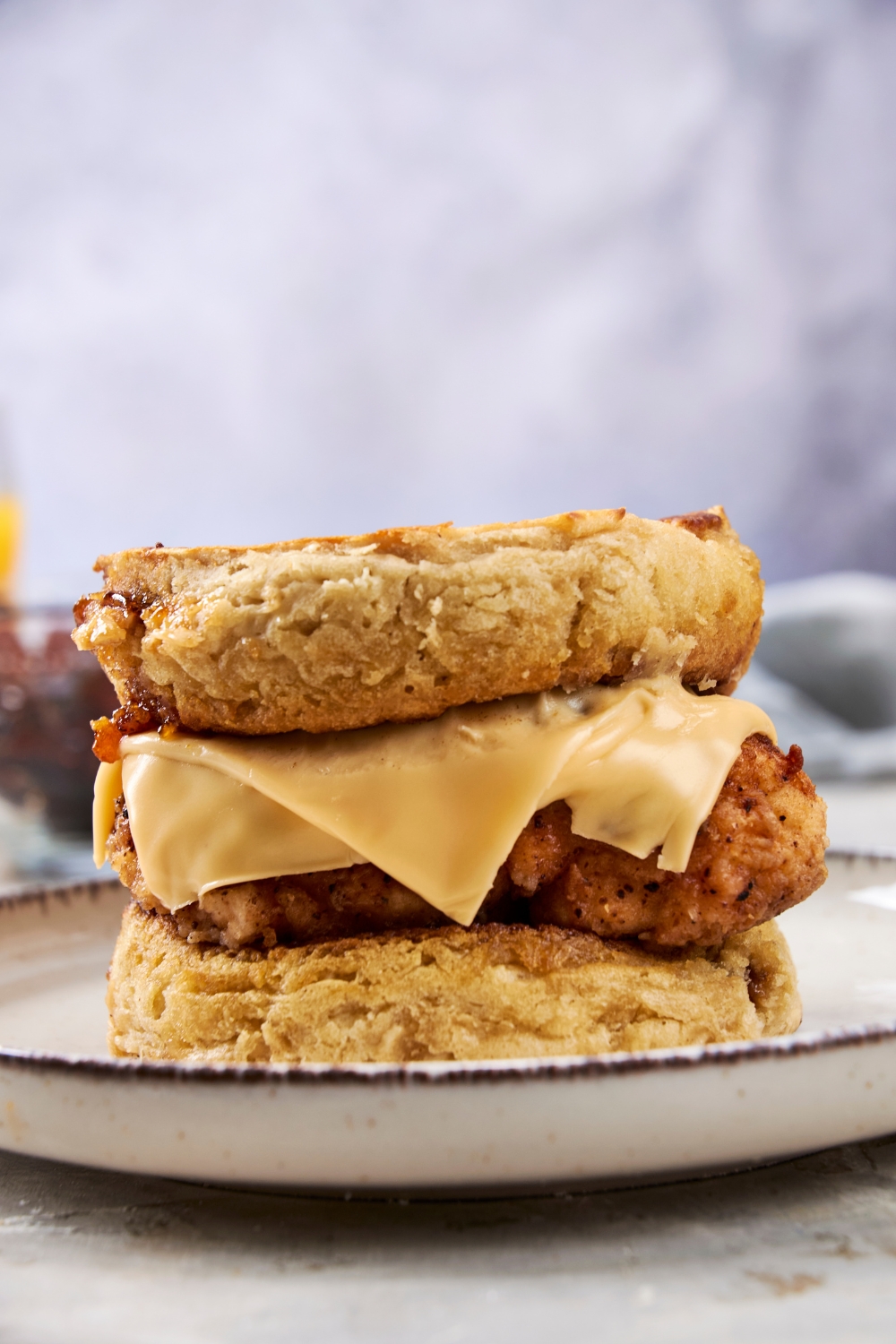 A crispy fried piece of chicken is topped with sliced cheese and sandwiched between two fluffy hotcakes.